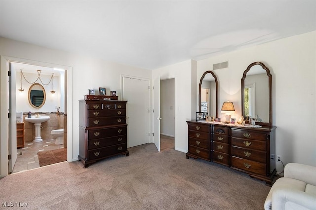 bedroom featuring visible vents, a sink, connected bathroom, and light colored carpet