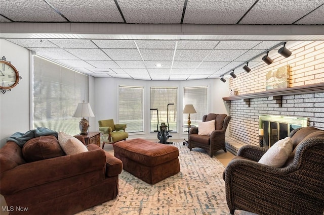 living room featuring track lighting, a brick fireplace, and a paneled ceiling