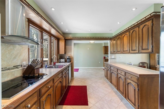 kitchen with wall chimney range hood, light tile patterned flooring, black electric stovetop, a sink, and backsplash