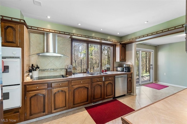 kitchen with wall chimney range hood, stainless steel dishwasher, white double oven, light tile patterned floors, and black electric stovetop