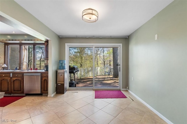 doorway to outside with baseboards, a sink, and light tile patterned flooring