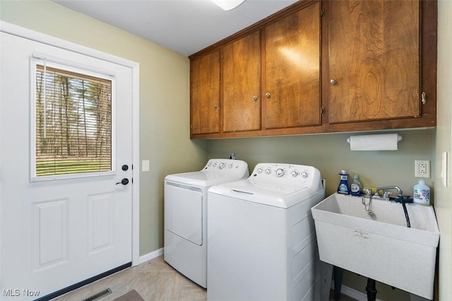laundry room featuring separate washer and dryer, a sink, cabinet space, and baseboards