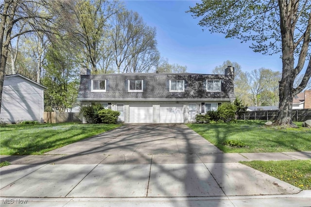 view of front of property featuring mansard roof, fence, a chimney, and a front lawn