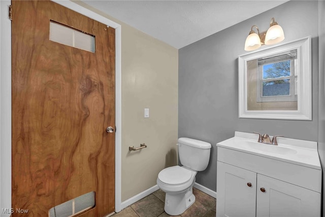 half bathroom with vanity, toilet, tile patterned floors, baseboards, and visible vents