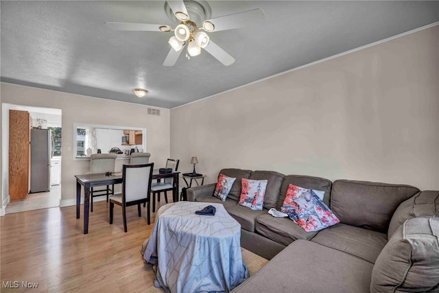 living area with baseboards, a ceiling fan, light wood-type flooring, and visible vents