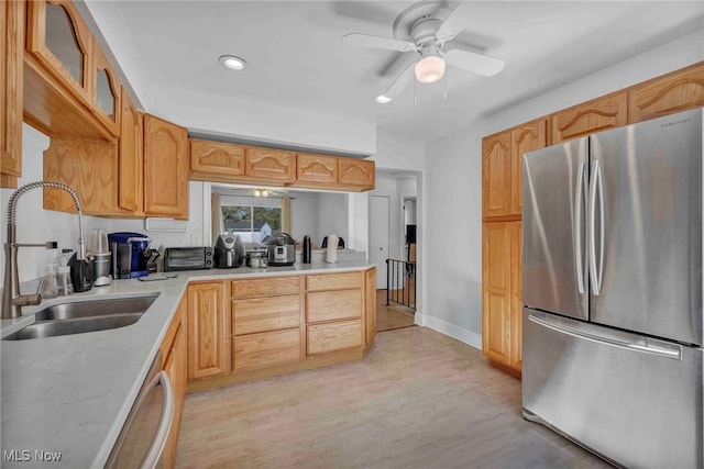 kitchen with a ceiling fan, glass insert cabinets, light countertops, a sink, and stainless steel appliances