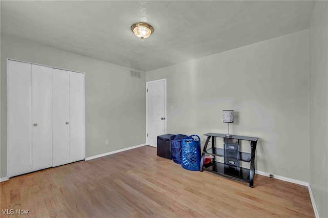 unfurnished bedroom with baseboards, visible vents, wood finished floors, and a closet