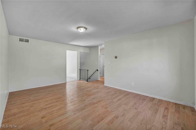 empty room featuring baseboards, wood finished floors, and visible vents