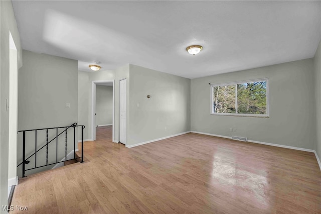 spare room featuring baseboards, visible vents, and wood finished floors