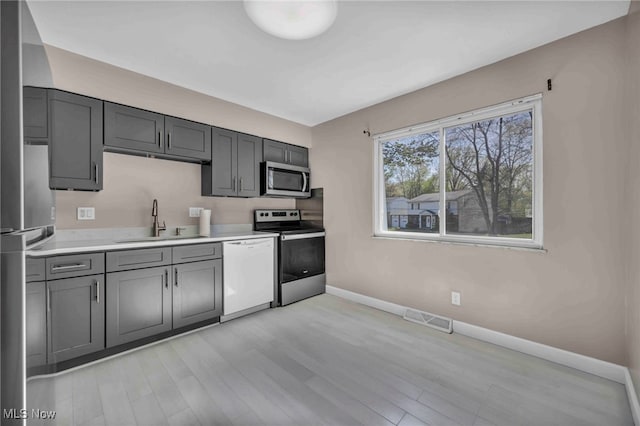 kitchen featuring visible vents, appliances with stainless steel finishes, a sink, baseboards, and light countertops