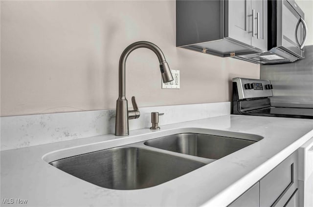 room details featuring a sink, light countertops, and stainless steel appliances