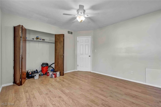 unfurnished bedroom with a ceiling fan, visible vents, wood finished floors, baseboards, and a closet