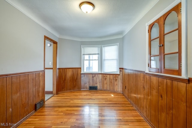 3860 Colony Rd, South Euclid, OH 44118 - spare room with visible vents, wood walls, wainscoting, and wood finished floors