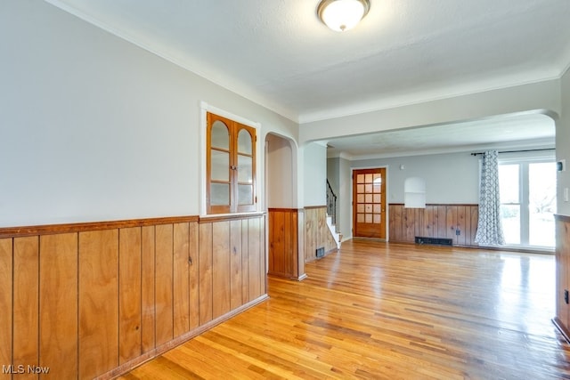 3860 Colony Rd, South Euclid, OH 44118 - unfurnished room with arched walkways, wainscoting, wood walls, light wood-type flooring, and stairway