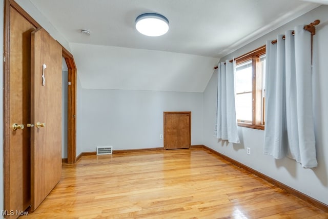 bonus room with light wood-style floors, baseboards, visible vents, and lofted ceiling