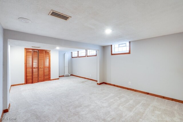 basement with baseboards, a textured ceiling, and visible vents