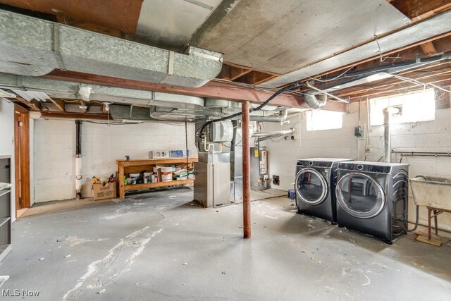 below grade area with a sink, heating unit, and washer and clothes dryer