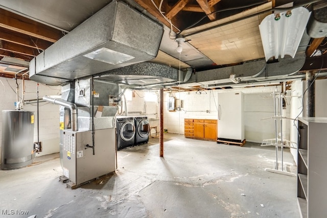 unfinished below grade area featuring water heater, concrete block wall, heating unit, and independent washer and dryer