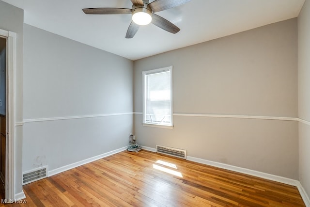 spare room featuring baseboards, visible vents, and wood finished floors