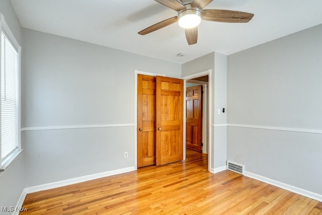 unfurnished bedroom featuring baseboards, multiple windows, light wood-type flooring, and visible vents