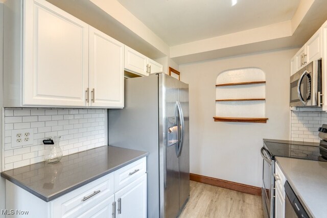 kitchen featuring white cabinetry, appliances with stainless steel finishes, decorative backsplash, and light wood finished floors