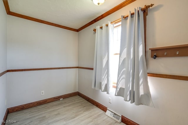 empty room with visible vents, baseboards, crown molding, and wood finished floors