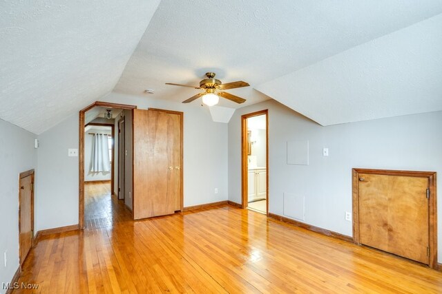 additional living space with a textured ceiling, light wood-style flooring, and lofted ceiling
