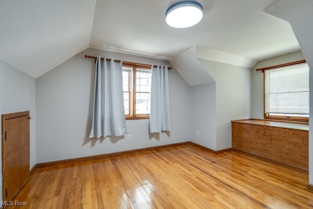 additional living space featuring baseboards, light wood-style flooring, and lofted ceiling