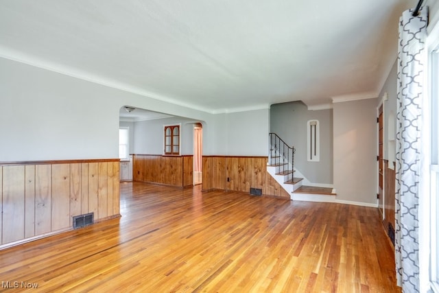 3860 Colony Rd, South Euclid, OH 44118 - unfurnished room featuring visible vents, arched walkways, a wainscoted wall, light wood-style floors, and stairs