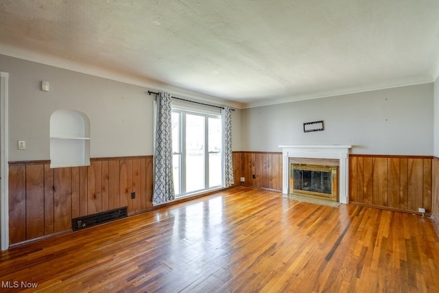 3860 Colony Rd, South Euclid, OH 44118 - unfurnished living room with a fireplace with flush hearth, wainscoting, wood finished floors, wooden walls, and ornamental molding