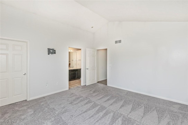 unfurnished bedroom with visible vents, carpet floors, baseboards, high vaulted ceiling, and connected bathroom
