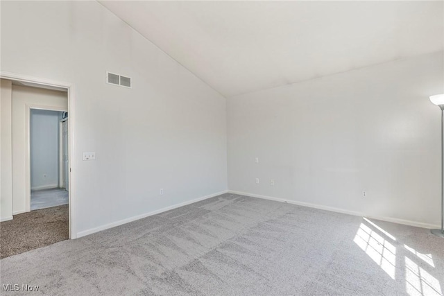 spare room with carpet flooring, baseboards, visible vents, and high vaulted ceiling