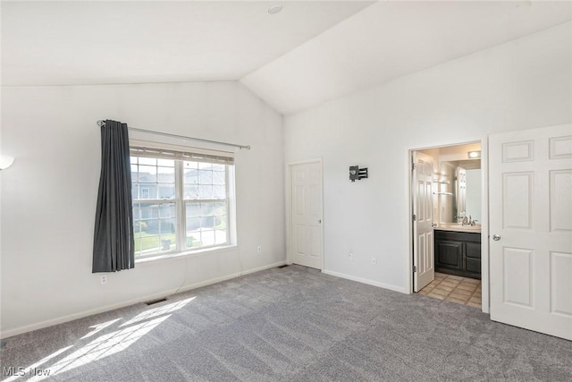 unfurnished bedroom with visible vents, light carpet, baseboards, ensuite bathroom, and high vaulted ceiling