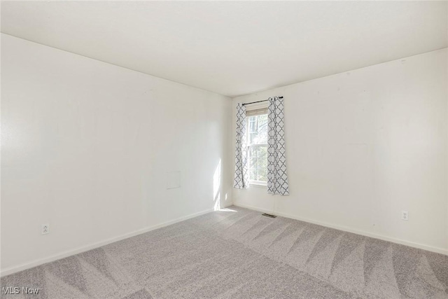 spare room with carpet floors, baseboards, and visible vents