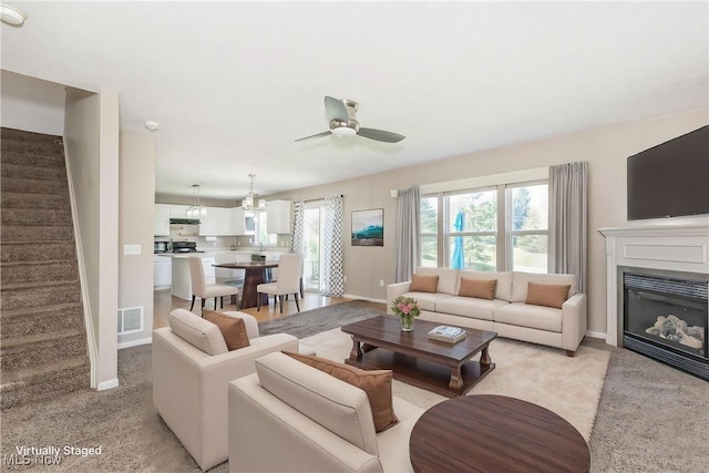 living room with baseboards, ceiling fan, stairs, and visible vents