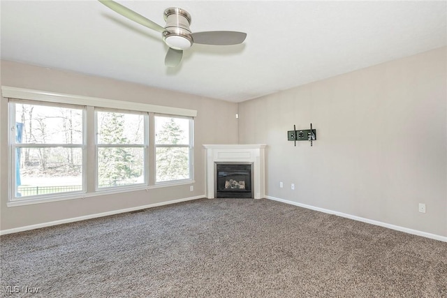 unfurnished living room featuring baseboards, a ceiling fan, and plenty of natural light
