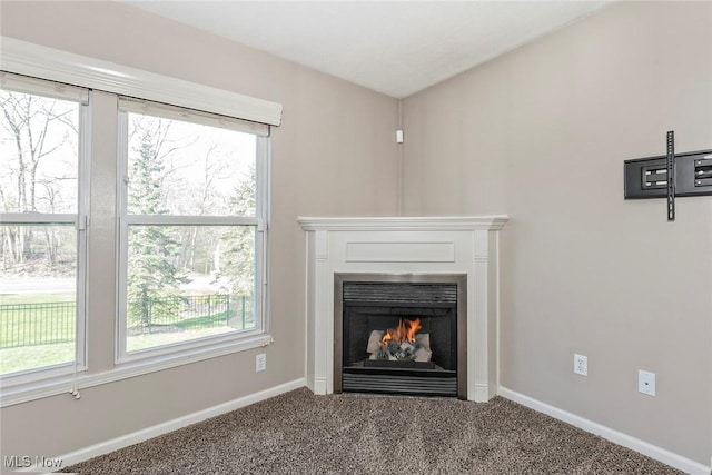 room details with baseboards, carpet, and a lit fireplace