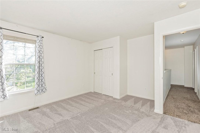 unfurnished bedroom featuring carpet floors, a closet, visible vents, and multiple windows