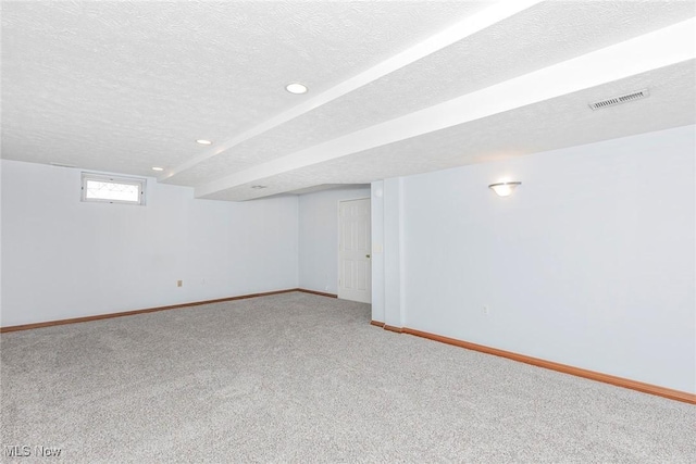 basement featuring a textured ceiling, carpet, recessed lighting, baseboards, and visible vents