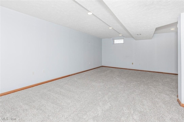below grade area featuring carpet floors, a textured ceiling, baseboards, and recessed lighting