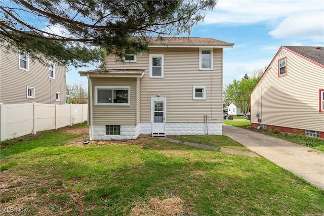 back of property featuring a lawn and fence