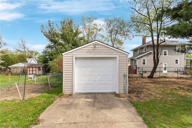 detached garage with concrete driveway and fence