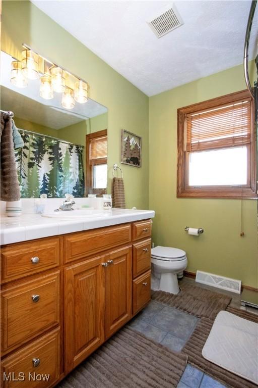 full bathroom with vanity, tile patterned floors, toilet, and visible vents