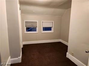 unfurnished room featuring baseboards and lofted ceiling
