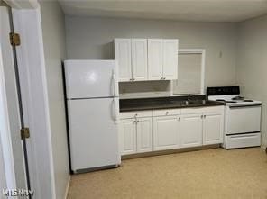 kitchen with white appliances, white cabinets, dark countertops, and a sink