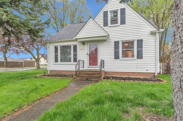 bungalow with roof with shingles, fence, and a front lawn
