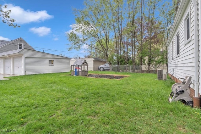 view of yard with central air condition unit, fence, and a garage