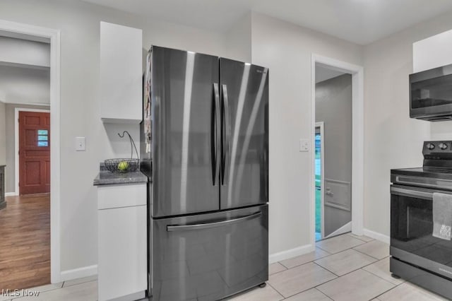 kitchen featuring dark countertops, appliances with stainless steel finishes, modern cabinets, baseboards, and white cabinets