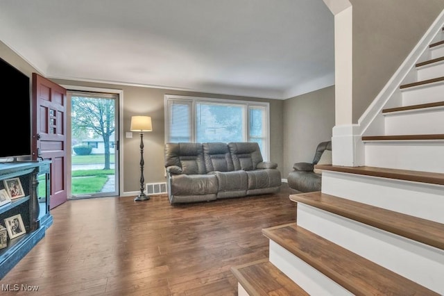 living area with stairs, baseboards, visible vents, and dark wood-type flooring