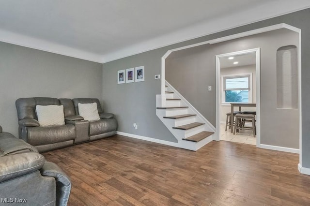 living room featuring baseboards, stairs, and wood finished floors